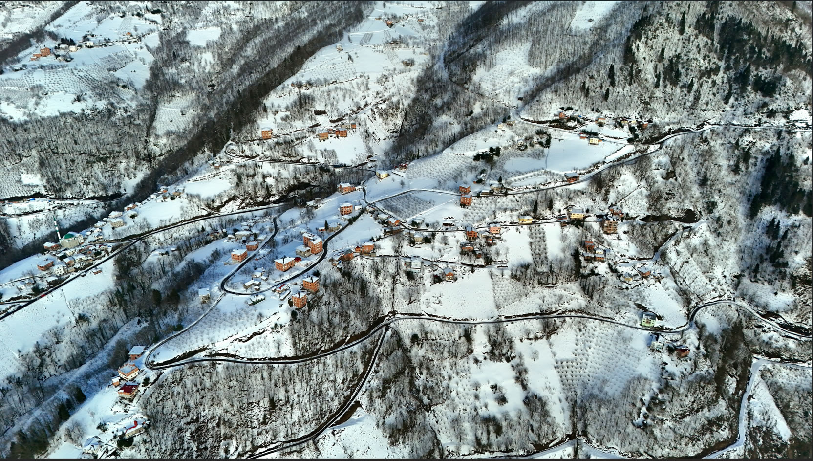 Kar altında Turalıuşağı köyü genel görünümü ve karlı dağlar.